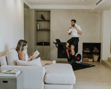 Usuario de una bicicleta indoor ZYCLE junto a otra persona que lee en el sofá